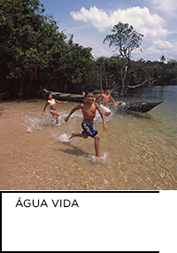 Fotografia. Três crianças correndo em rio raso. Abaixo, “ÁGUA VIDA”.