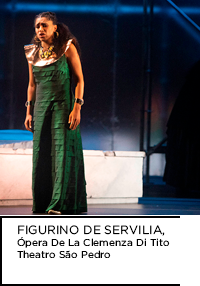 Fotografia. Mulher em vestido verde cantando. Abaixo, “FIGURINO DE SERVILIA, Ópera de La Clemenza Di Tito Theatro São Pedro”.