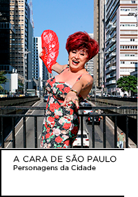 Fotografia. Nany People no centro da imagem e a cidade de São Paulo ao fundo.